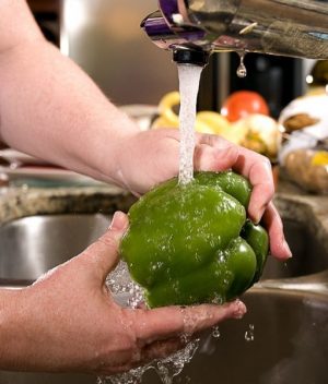 Washing a green bell pepper under some fresh running tap water